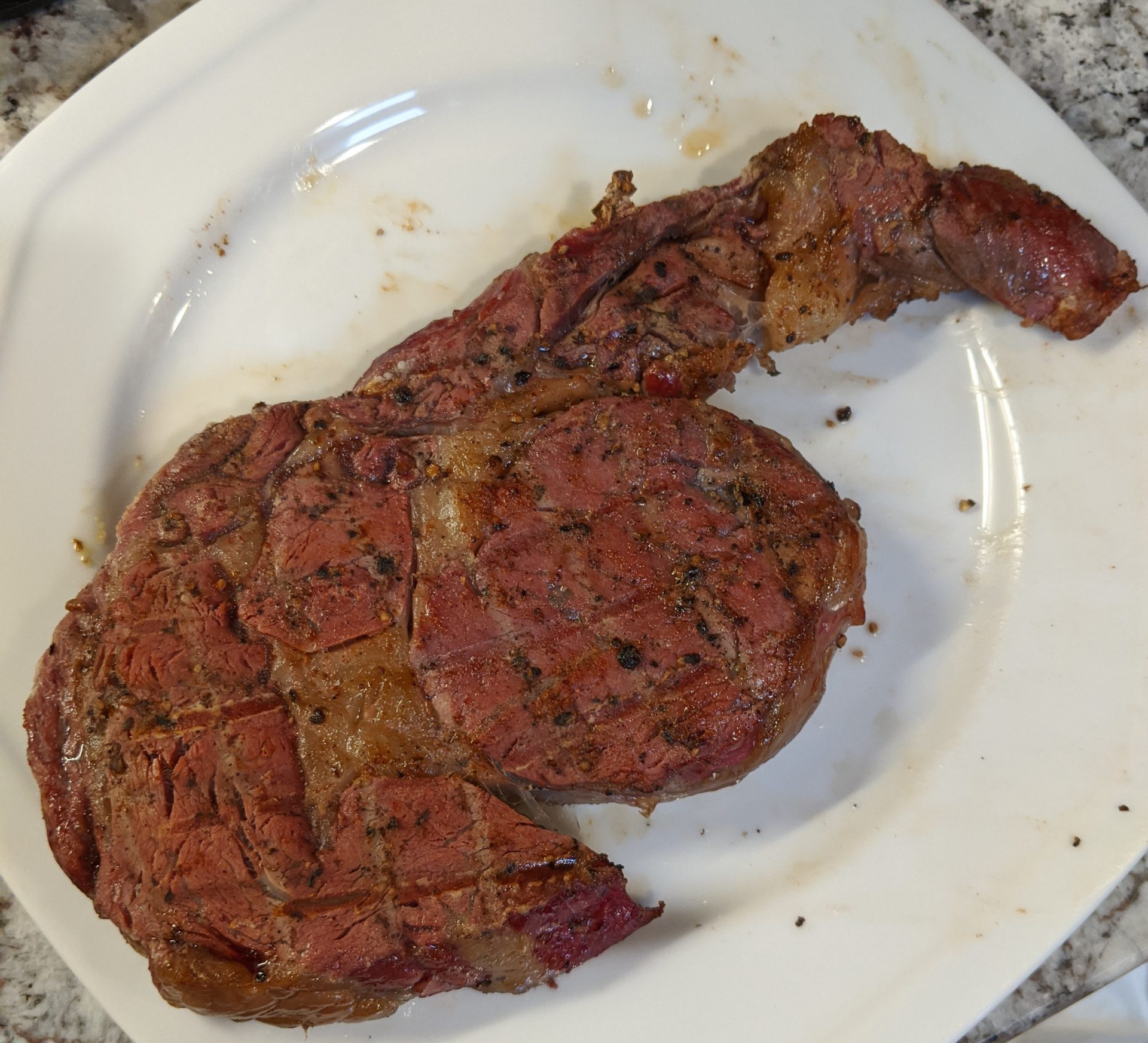 Reverse seared ribeye steak on a white dinner plate