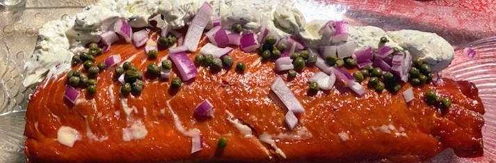 smoked salmon on glass plate with red onion, herb cream cheese, and capers